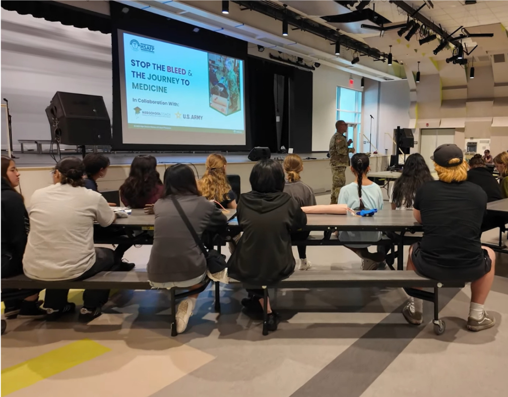 High school students watching army medics teach a hands-on medical workshop